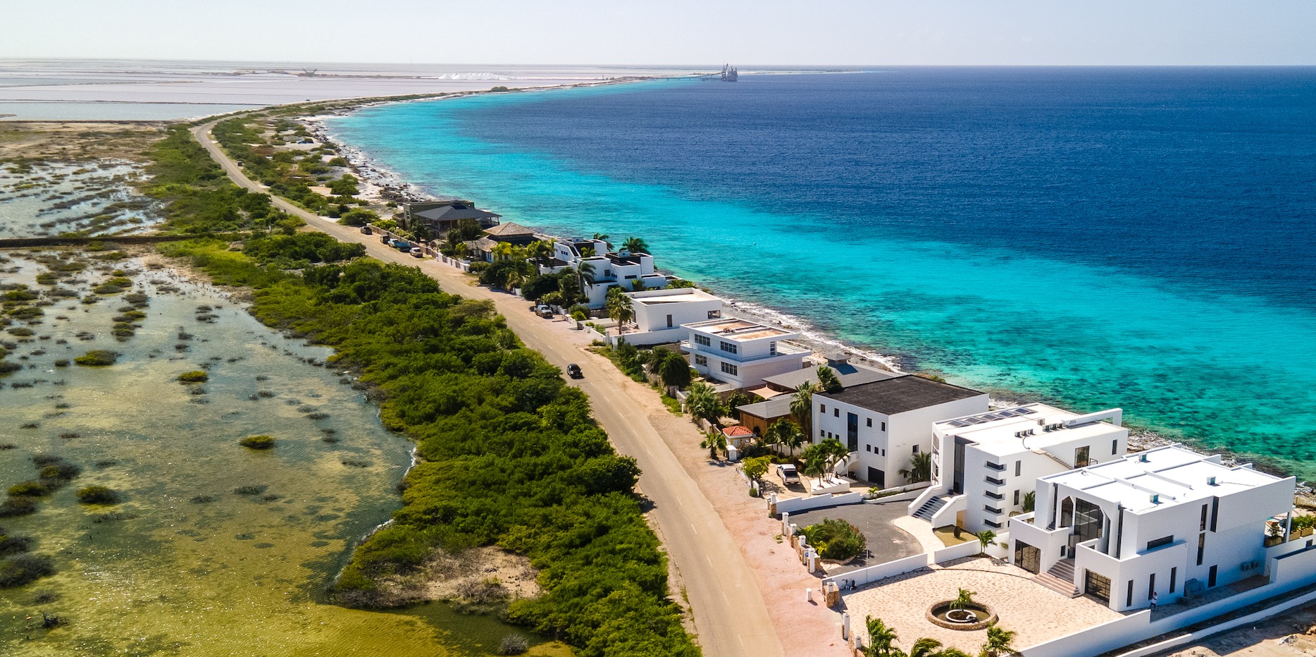 Aerial view of luxury Bonaire villas with modern white architecture on the stunning turquoise coastline of the Caribbean Sea.